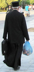 A Greek Orthodox priest carries his shopping home at The Cheshire Cat Blog