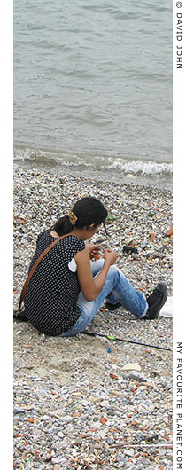 A young woman fishing on the town beach of Kusadasi, Turkey