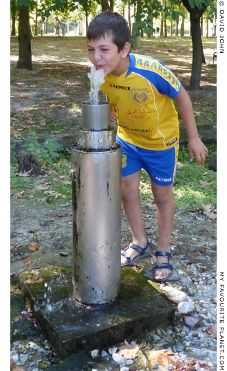 A young visitor drinking from a water fountain in Dion Archaeological Park at The Cheshire Cat Blog