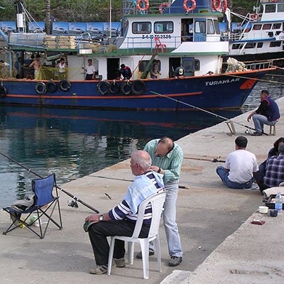 Angler having his hair cut on the causeway to Guvercin Ada (Pigeon Island), Kusadasi, Turkey at My Favourite Planet