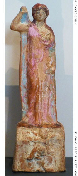 A multicoloured ceramic figurine of a female figure lifing the edge of her peplos at My Favourite Planet