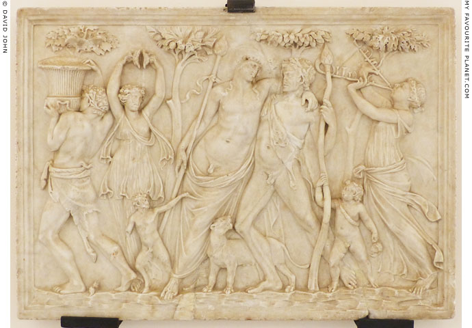 A marble relief with drunken Dionysus supported by a Satyr between two Maenads at My Favourite Planet