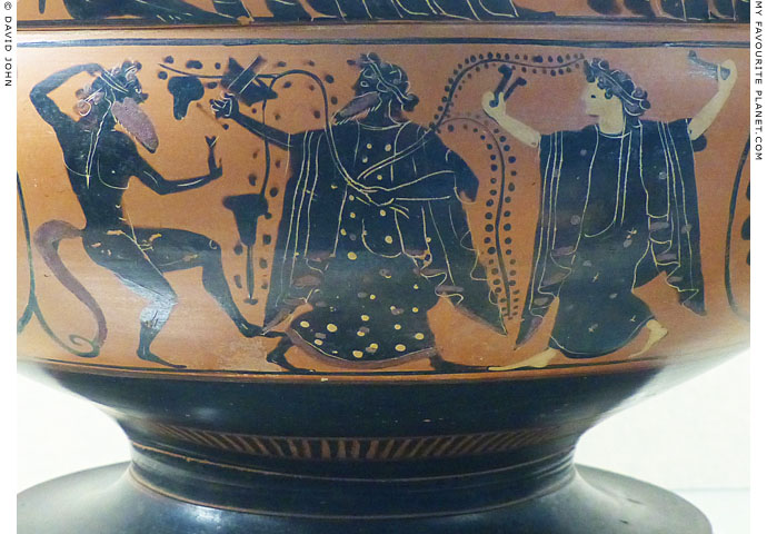Dionysus standing between a Satyr and a Maenad playing krotala at My Favourite Planet